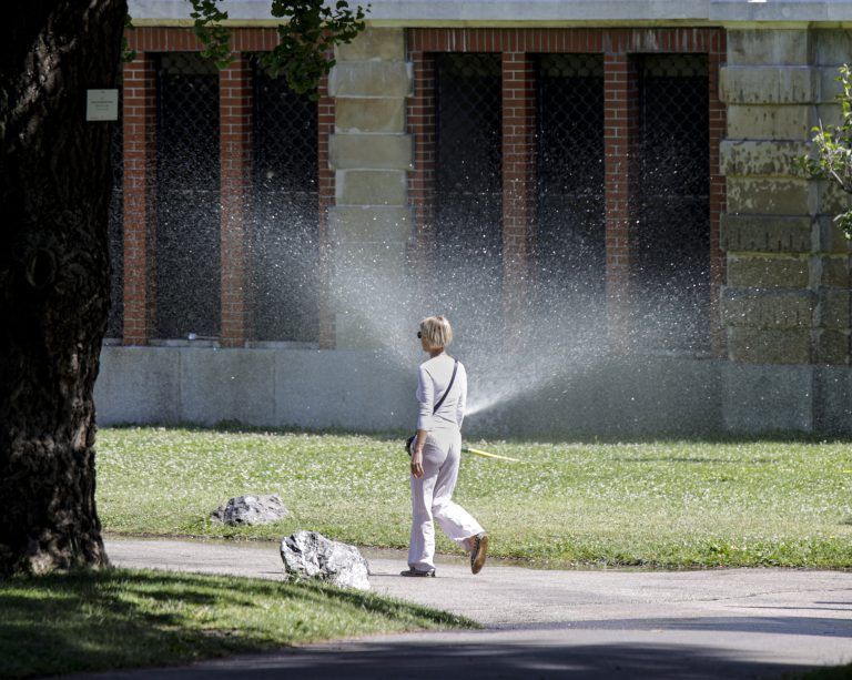 Eine Frau spaziert vor einer Rasensprinkleranlage im Volksgarten in Wien. <span class="copyright">(C) APA/TOBIAS STEINMAURER (THEMENBILD)</span>