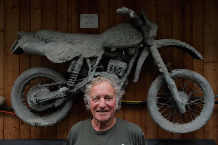 Peter Hinterreiter vor einer in Beton gegossenen Motocross, die an seiner Garage hängt. <span class="copyright">hartinger</span>