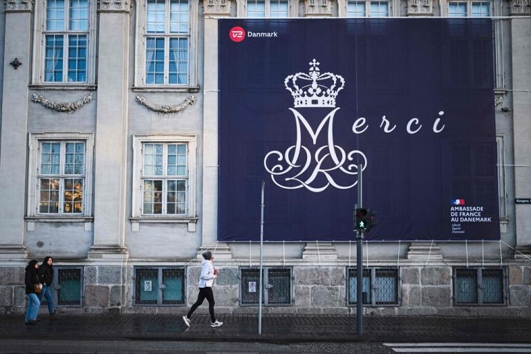 A man runs by a huge placard reading “Merci” and hanging on the facade of the French embassy ahead of the proclamation of abdication of Denmark's Queen Margrethe II, in Copenhagen, Denmark, on January 14, 2024. Denmark turns a page in its history on January 14 when Queen Margrethe abdicates and her son becomes King Frederik X, with more than 100,000 Danes expected to turn out for the unprecedented event. (Photo by Jonathan NACKSTRAND / AFP)