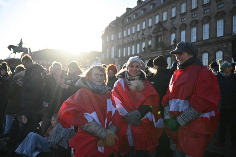 People wrapped in flags of Denmark and warm clothes gather in the early morning at Christiansborg Palace Square in front of the balcony, ahead of the proclamation of abdication of Denmark's Queen Margrethe II, in Copenhagen, Denmark, on January 14, 2024. Denmark turns a page in its history on January 14 when Queen Margrethe abdicates and her son becomes King Frederik X, with more than 100,000 Danes expected to turn out for the unprecedented event. (Photo by Jonathan NACKSTRAND / AFP)