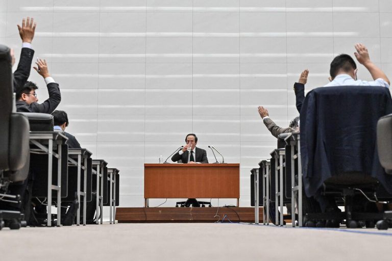 Bank of Japan (BoJ) governor Kazuo Ueda (C) has a drink of water as journalists raise their hands to ask questions during a press conference after a two-day monetary policy meeting at the BOJ headquarters in Tokyo on March 19, 2024. Japan's central bank pulled the plug on March 19 on its ultra-aggressive monetary stimulus programme, hiking rates for the first time since the global financial crisis. (Photo by Richard A. Brooks / AFP)