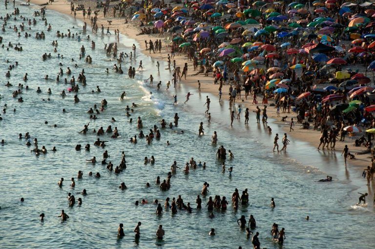 TOPSHOT - Aerial view of people enjoying Recreio dos Bandeirantes beach amid a heat wave in Rio de Janeiro, Brazil, taken on March 17, 2024. A new heat wave is hitting Brazil, with record temperatures that drove residents of Rio de Janeiro and Sao Paulo on Sunday to pour onto beaches and parks. In western Rio, the wind chill touched 60.1 degrees Celsius on Saturday, a maximum since the Sistema Alerta Rio began making these measurements in 2014. (Photo by TERCIO TEIXEIRA / AFP)