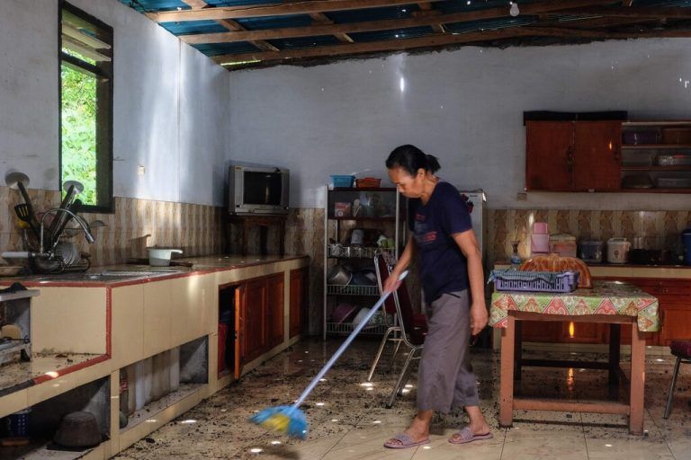 A woman sweeps the floor after volcanic material from the recent eruptions of Mount Ruang volcano fell through the roof of a building on Tagulandang island in Sitaro, North Sulawesi on April 19, 2024. Indonesian authorities were on alert on April 19 for more eruptions from a remote island volcano that forced thousands to evacuate this week, as nearby residents began clearing debris after molten rocks rained down on their villages. (Photo by Ronny Adolof BUOL / AFP)