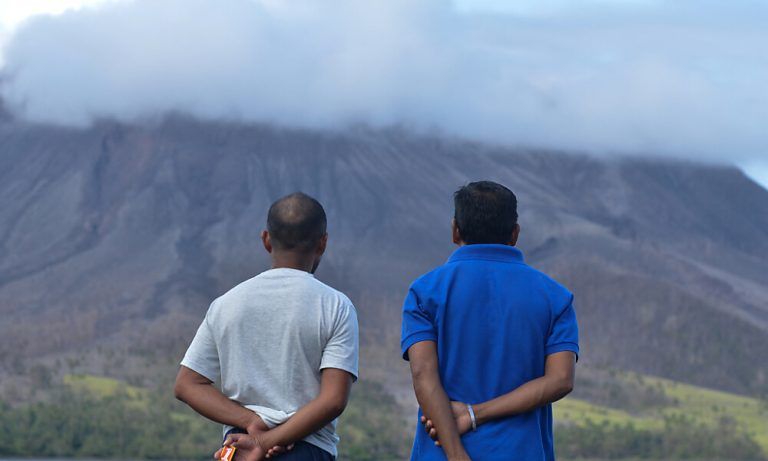 People look at the Mount Ruang volcano from the port on Tagulandang island in Sitaro, North Sulawesi on April 19, 2024. (Photo by Ronny Adolof BUOL / AFP)
