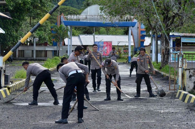 Police officers sweep volcanic material accumulated on the ground, after eruptions of the Mount Ruang volcano, on Tagulandang island in Sitaro, North Sulawesi on April 19, 2024. (Photo by Ronny Adolof BUOL / AFP)