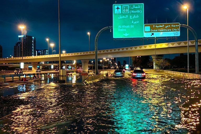 TOPSHOT - Motorisits drive along a flooded street following heavy rains in Dubai early on April 17, 2024. Dubai, the Middle East's financial centre, has been paralysed by the torrential rain that caused floods across the UAE and Bahrain and left 18 dead in Oman on April 14 and 15. (Photo by Giuseppe CACACE / AFP)