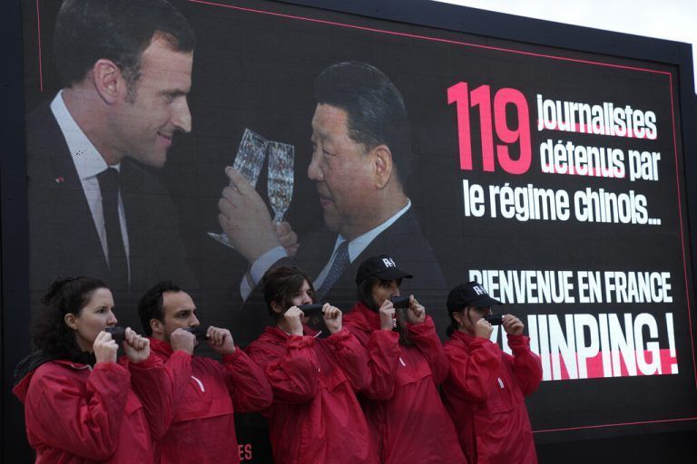 Members of RSF (Reporters without Borders) pose with gags in front of the Arc de Triomphe to denounce the imprisonment of journalists in China, Monday, May 6, 2024 in Paris. French President Emmanuel Macron is welcoming China's Xi Jinping for a two-day state visit to France and is seeking to press Xi to use his influence on Moscow to move toward ending the war in Ukraine. (AP Photo/Christophe Ena)