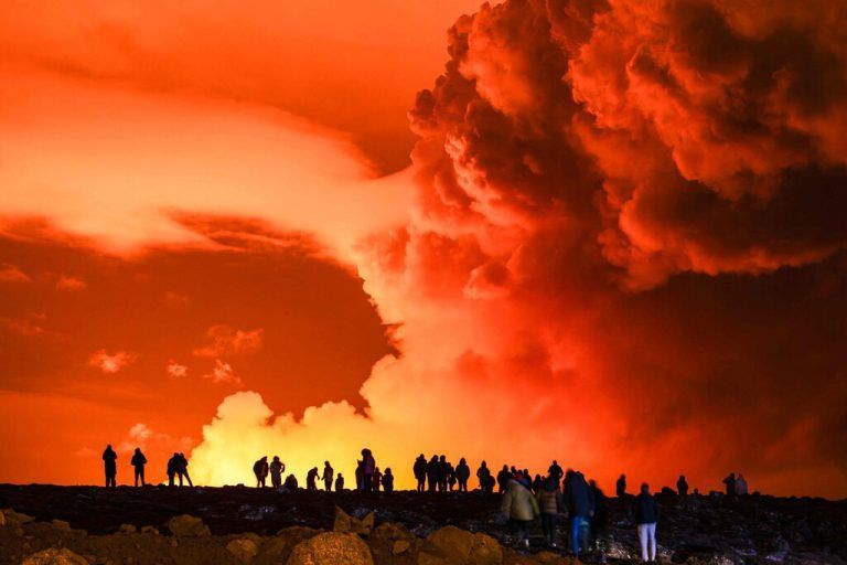 (FILES) People gather to watch as molten lava flows out from a fissure on the Reykjanes peninsula north of the evacuated town of Grindavik, western Iceland on March 16, 2024. A new volcanic eruption is expected at any moment on the Reykjanes peninsula in southwestern Iceland, the Icelandic Metereological Office said on May 29, 2024, prompting authorities to again evacuate the lava-hit town of Grindavik. (Photo by Ael Kermarec / AFP)