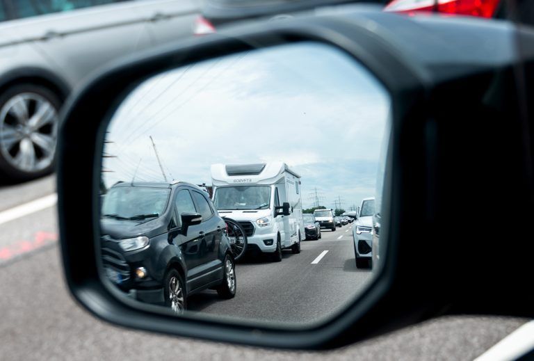 ABD0121_20240706 – HAMBURG – DEUTSCHLAND: 06.07.2024, Hamburg: Reiseverkehr steht auf der Autobahn A7 vor dem Elbtunnel in Richtung Norden im Stau und spiegelt sich im Rckspiegel eines Autos. Foto: Daniel Bockwoldt/dpa +++ dpa-Bildfunk +++. – FOTO: APA/dpa/Daniel Bockwoldt