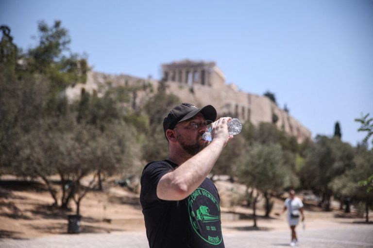 A tourist drinks water while standing near The Acropolis in Athens on July 12, 2024. Heat conditions heat are set to prevail across Greece for at least a week, according to meteorologist forecasts, and the maximum daily temperature is expected to exceed daily 38-40C in many areas reaching levels some 6-8C above normal for the season. (Photo by Aris Oikonomou / AFP)