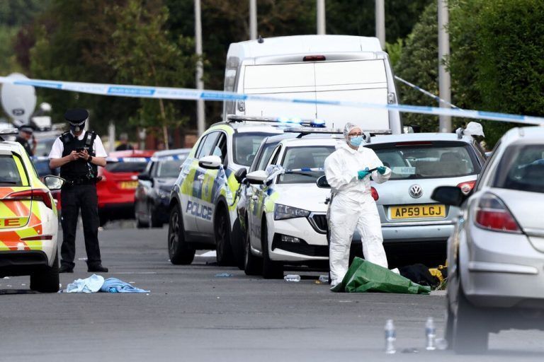 Police officers and forensic personnel stand behind a cordon on Hart Street in Southport, northwest England, on July 29, 2024, following a knife attack. A suspected knife attack in northern England left at least eight people injured, believed to include children, emergency services said. (Photo by Darren Staples / AFP)