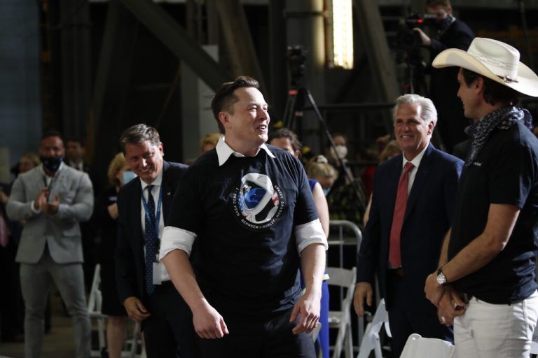 Tesla and SpaceX Chief Executive Officer Elon Musk stands as his brother Kimbal Musk, right, and House Minority Leader Kevin McCarthy of Calif., look on during an event at the Vehicle Assembly Building on Saturday, May 23, 2020, after a SpaceX flight at NASA's Kennedy Space Center in Cape Canaveral, Fla. A rocket ship designed and built by SpaceX lifted off on Saturday with two Americans on a history-making flight to the International Space Station. (AP Photo/Alex Brandon)
