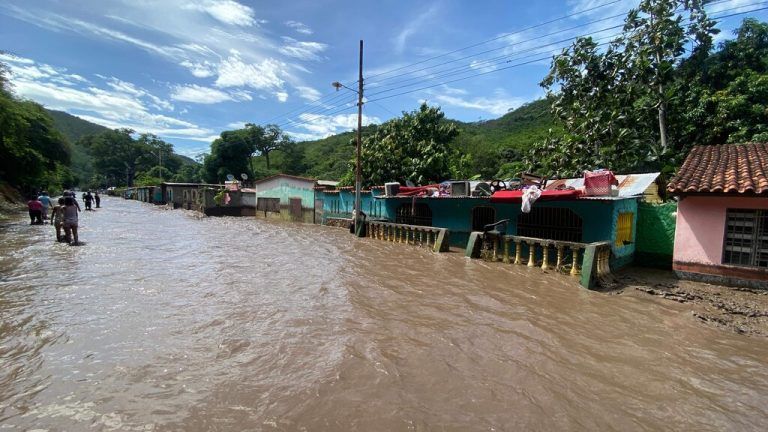 TOPSHOT - People stand outside their flooded homes after a river swelled due to heavy rains following the passage of Hurricane Beryl on the road from Cumana to Cumanacoa, Sucre State, Venezuela, on July 2, 2024. Hurricane Beryl churned towards Jamaica Tuesday after killing at least five people and causing widespread destruction across the southeastern Caribbean, threatening deadly winds and storm surge as it approached. (Photo by Victor GONZALEZ / AFP)