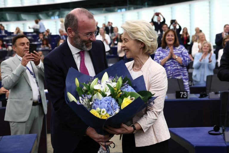 Ursula von der Leyen (R), a nominee for a second term as president of the European Commission receives flowers from with EU Parliament's political group European People's Party (EPP) President, Manfred Weber (L) at the European Parliament in Strasbourg, eastern France, on July 18, 2024. EU lawmakers on July 18 handed Ursula von der Leyen another five-year term as European Commission president during their first parliamentary session since June elections. Von der Leyen won with the support of 401 MEPs in the 720-seat chamber -- comfortably over the 361-vote majority she needed to remain head of the EU's executive body. There were 284 who voted against in the secret ballot. (Photo by FREDERICK FLORIN / AFP)