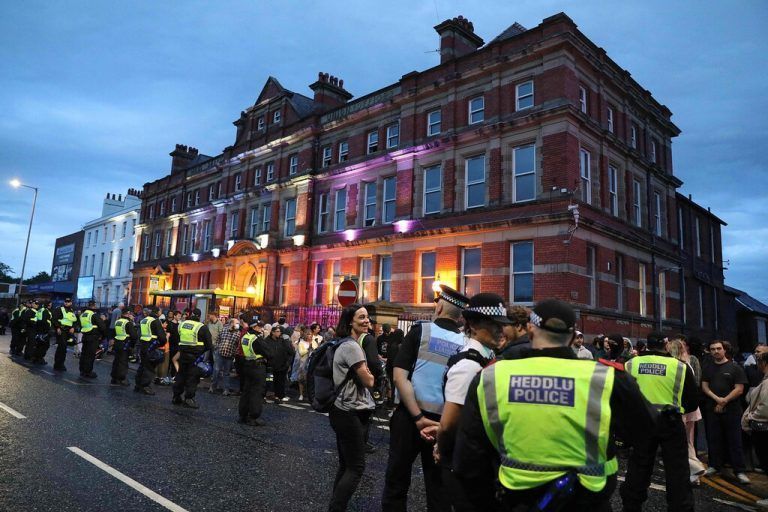 Police officers stand guard between protesters (back) defending the Abdullah Quilliam Mosque in Liverpool on August 2, 2024 against the 'Enough is Enough' demonstration (not seen) called in reaction to the fatal stabbings in Southport on July 29. UK police prepared for planned far-right protests and other demonstrations this weekend, after two nights of unrest in several English towns and cities following a mass stabbing that killed three young girls. (Photo by IAN COOPER / AFP)