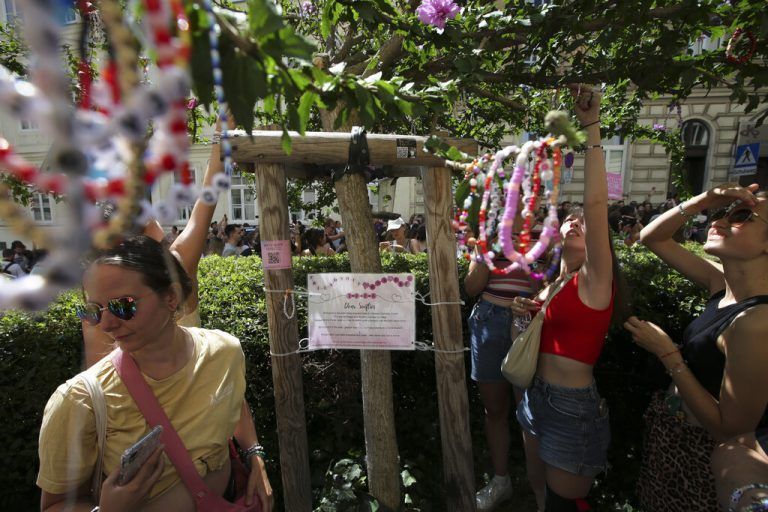 Swifties fix bracelets on a tree in the city centre in Vienna on Thursday, Aug.8, 2024. Organizers of three Taylor Swift concerts in the stadium in Vienna this week called them off on Wednesday after officials announced arrests over an apparent plot to launch an attack on an event in the Vienna area such as the concerts. (AP Photo/Heinz-Peter Bader)