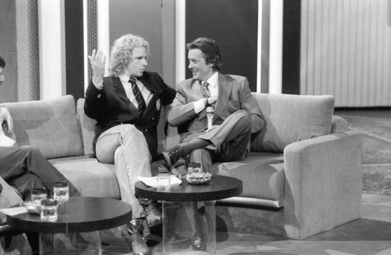Thomas Gottschalk li. mit Alain Delon 04/89 - Thomas Gottschalk li. und Alain Delon am 8. April 1989 in Wetten, dass.. ZDF in Saarbrücken Deutschland TV Fernsehen Show Frankreich Franzose französischer Mann Schauspiel Fernsehen Film Kino deutscher Moderator Moderation Show Kulisse Sofa Männer french actor quer ganz sitzend sprechend gestikulierend lächelnd sw