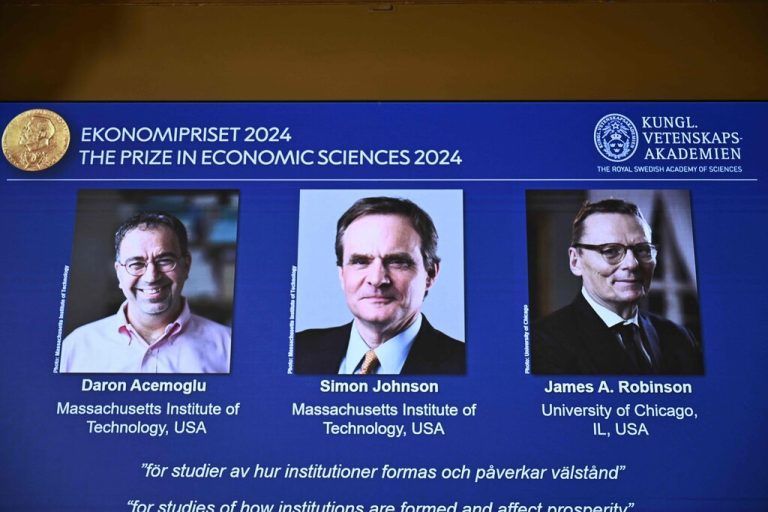 A screen shows the laureates (L-R) Turkish-American Daron Acemoglu and British-Americans Simon Johnson and James Robinson of the 2024 Sveriges Riksbank Prize in Economic Sciences in Memory of Alfred Nobel during the announcement by the Royal Swedish Academy of Sciences in Stockholm, Sweden on October 14, 2024. (Photo by Christine OLSSON / TT NEWS AGENCY / AFP) / Sweden OUT