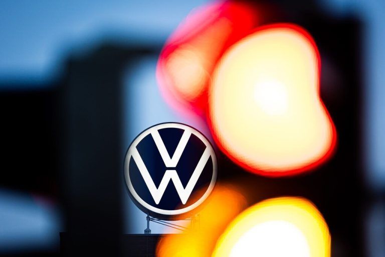 ABD0087_20241015 - WOLFSBURG - DEUTSCHLAND: ARCHIV - 04.09.2024, Niedersachsen, Wolfsburg: Das VW-Logo leuchtet auf dem Dach des Markenhochhauses im Volkswagen Stammwerk am frühen Morgen hinter einer rot-gelb zeigenden Ampel. Volkswagen hat angekündigt, wegen der angespannten Lage der Kernmarke den Sparkurs zu verschärfen. Auch betriebsbedingte Kündigungen und Werksschließungen könnten nicht länger ausgeschlossen werden. (zu dpa: «Arbeitsgericht: Keine Gehaltserhöhung für Ex-VW-Manager») Foto: Moritz Frankenberg/dpa +++ dpa-Bildfunk +++. - FOTO: APA/dpa/Moritz Frankenberg