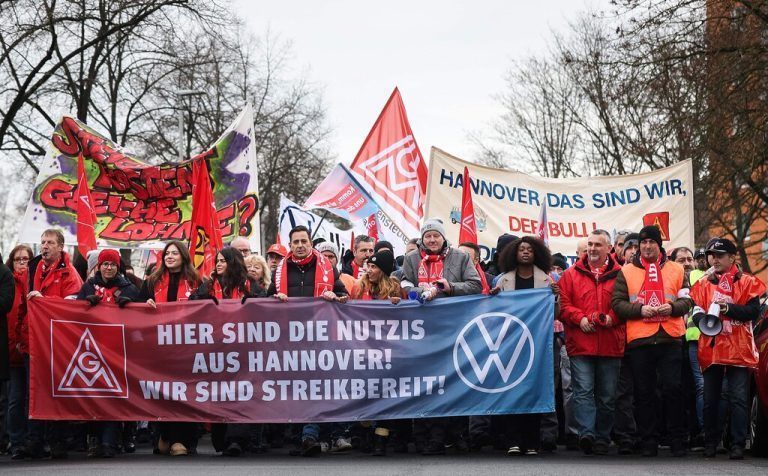 Employees of German car maker Volkswagen (VW) demonstrate outside the VW commercial cars plant on December 2, 2024 in Hanover, northern Germany, as thousands of Volkswagen workers go on strike all over Germany in an escalating industrial dispute at the crisis-hit German auto giant with thousands of jobs at stake. VW has been hit hard by high manufacturing costs at home, a stuttering shift to electric vehicles and tough competition in key market China. It has announced a plan to cut billions of dollars in costs. (Photo by Ronny HARTMANN / AFP)