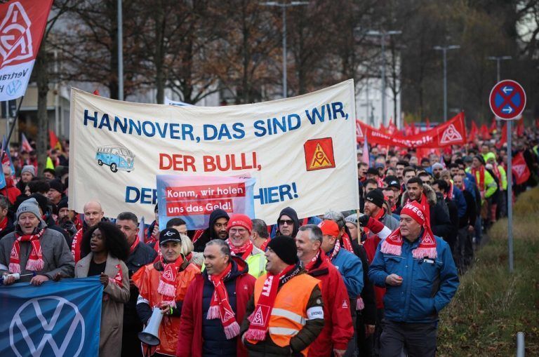 Employees of German car maker Volkswagen (VW) demonstrate outside the VW commercial cars plant on December 2, 2024 in Hanover, northern Germany, as thousands of Volkswagen workers go on strike all over Germany in an escalating industrial dispute at the crisis-hit German auto giant with thousands of jobs at stake. VW has been hit hard by high manufacturing costs at home, a stuttering shift to electric vehicles and tough competition in key market China. It has announced a plan to cut billions of dollars in costs. (Photo by Ronny HARTMANN / AFP)