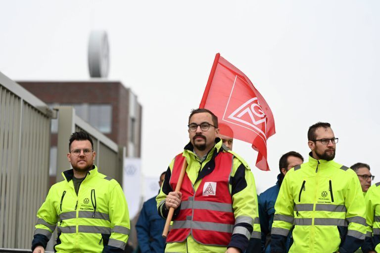 IG Metall ruft zu flächendeckenden Streiks in VW-Werken auf. Mitarbeiter ziehen mit einer IG-Metall Flagge über das Volkswagen Gelände. Die IG Metall fordert Lohnerhöhungen, VW will seinen Arbeitern weniger bezahlen. Nun beginnen flächendeckende Streiks an den deutschen Standorten des Autoherstellers. Emden Niedersachsen Deutschland *** IG Metall calls for nationwide strikes at VW plants Employees march across the Volkswagen site with an IG Metall flag IG Metall demands wage increases, VW wants to pay its workers less Now nationwide strikes begin at the car manufacturers German sites Emden Lower Saxony Germany Copyright: xdiebildwerftx