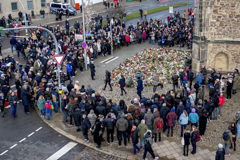 People gather to lay flowers and light candles at the entrance of the Johannis church near the Christmas Market, where a car drove into a crowd on Friday evening, in Magdeburg, Germany, Sunday, Dec. 22, 2024. (AP Photo/Michael Probst)